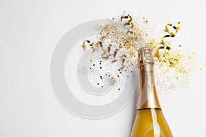 Bottle of champagne with gold glitter, confetti and space for text on white background, top view. Hilarious