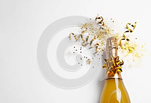 Bottle of champagne with gold glitter, confetti and space for text on white background, top view.