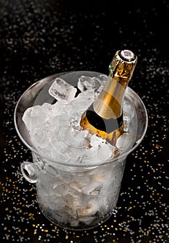 Bottle of Champagne in an ice bucket against a festive background and straw huts