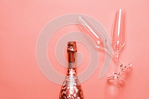 Bottle of champagne  or sparkling wine with a couple of glasses on pink background