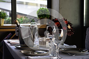 A bottle of champagne or sparkling wine in an ice bucket on a cafe or restaurant table for several guests.