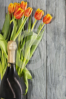 A bottle of champagne and Tulip flowers. the holiday is March 8, mother`s Day. Romantic setting