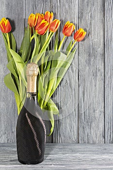 a bottle of champagne and Tulip flowers. the holiday is March 8, mother's Day. Romantic setting.