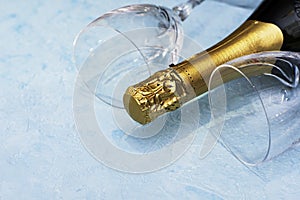 a bottle of champagne and two glass glasses lying on a blue background close-up