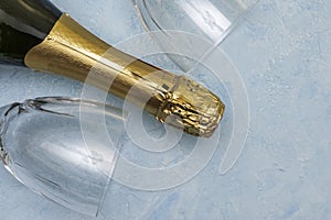 a bottle of champagne and two glass glasses lying on a blue background close-up