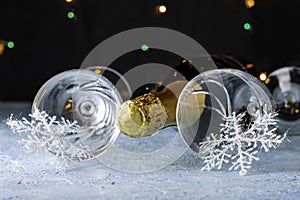 A bottle of champagne and two glass glasses with snowflakes on legs on a black background with backlight