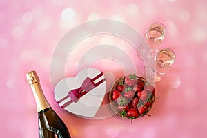 Bottle of champagne, two glasses of champagne, heart shape gft box and fresh strawberry on pink background