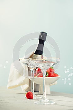 Bottle of champagne, two glasses and strawberries on sea and sky background