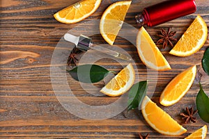 Bottle of citrus essential oil and orange slices on wooden table