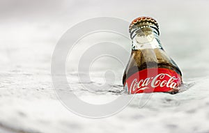 A bottle of Coca-Cola in the icy water.