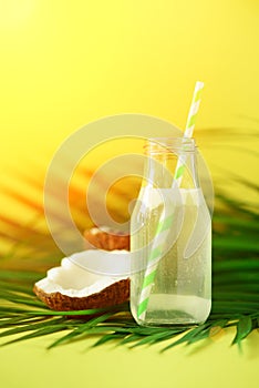 Bottle of coconut water and fresh ripe fruits on yellow background. Summer food concept. Vegetarian, vegan, detox drink