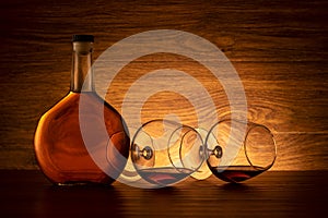 A bottle of cognac and two wine glasses on the table