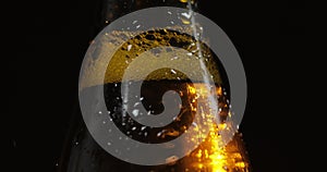 Bottle of cold beer on a black background. It slowly rotates. Condensate