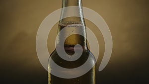 A bottle of cold beer slowly rotates against a dark background. Cold light beer close-up. 360 degree rotation