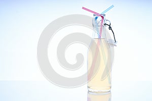 Bottle with cold drink on glass table with two straws