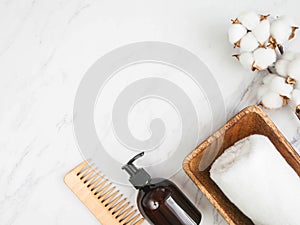 Bottle container with pump mock up, towel, wooden hair comb on white marble background