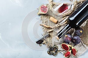 Bottle, corkscrew, glass of red wine, figs on a table
