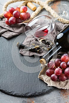 Bottle, corkscrew, glass of red wine, grapes on a table