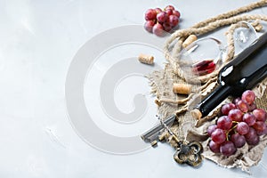 Bottle, corkscrew, glass of red wine, grapes on a table