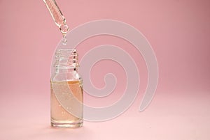 Bottle of cosmetic oil, serum skin care products on a pink background. Place for text