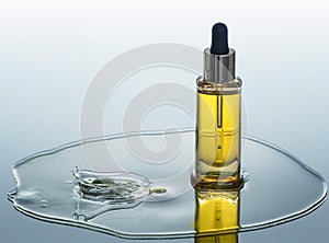 The bottle of cosmetic oil stands on the water background with splash