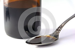 Bottle and cough syrup in a spoon. Close Up of a natural cough medicine in a spoon. Concept: treatment and health