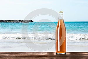 Bottle of delicious kvass on wooden table near sea. Space for text