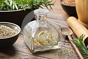 Bottle of dry herbs for making healing infusion or tincture. Bowls of medicinal plants and wooden mortar on background.