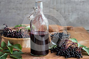 A bottle of elderberry syrup on a wooden background