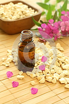 Bottle of essence oil with flowers and stones