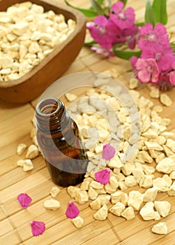 bottle of essence oil with flowers and stones