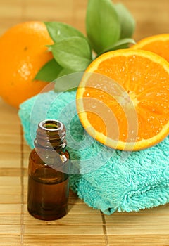 bottle of essence oil, towel and fresh oranges