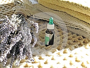 Bottle of essential oil across white towels and lavender bouquet. Cosmetics. Spa. Aromatherapy