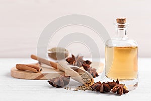 Bottle of essential oil, anise and seeds on white wooden table