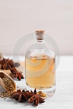 Bottle of essential oil, anise and seeds on white wooden table