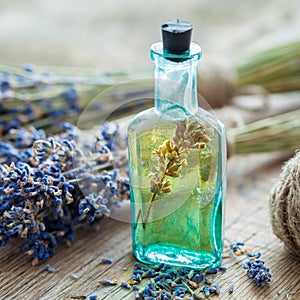 Bottle of essential oil and bunch of lavender flowers