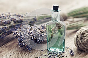 Bottle of essential oil and bunch of lavender flowers.