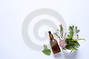 Bottle of essential oil, different herbs, rose flower and bud on white background, flat lay. Space for text