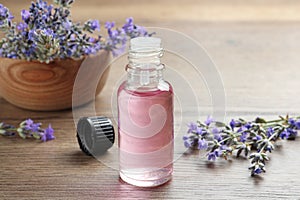 Bottle of essential oil and flowers on wooden table