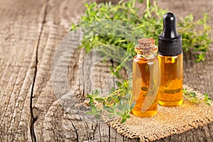 Bottle of essential oil with herbs thyme on white background