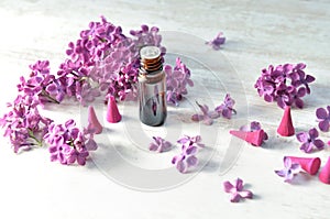 Bottle of essential oil and incense with purple lilac flower