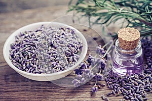 Bottle of essential oil and lavender flowers in bowl