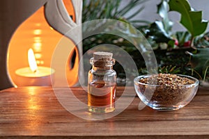A bottle of essential oil with myrrh resin and a candle