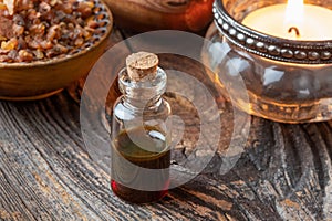 A bottle of essential oil with myrrh resin on a rustic background