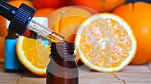 Bottle of essential oil from oranges on wooden background with pieces of oranges - alternative medicine. Essential aroma oil with