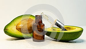 A bottle of essential oil, a pipette and fresh avocado on the table, Avocado oil in a dropper bottle and avocado.