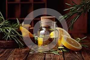Bottle of essential oil, rosemary, and lemon on a wooden table