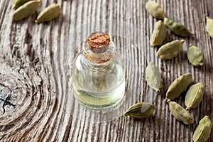 A bottle of cardamon essential oil with cardamon seeds