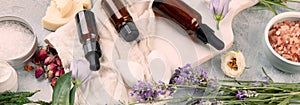 Bottle of essential oils with herbs and flowers on light gray background