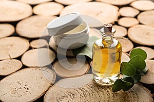 Bottle of eucalyptus essential oil and jar with cream on wooden background